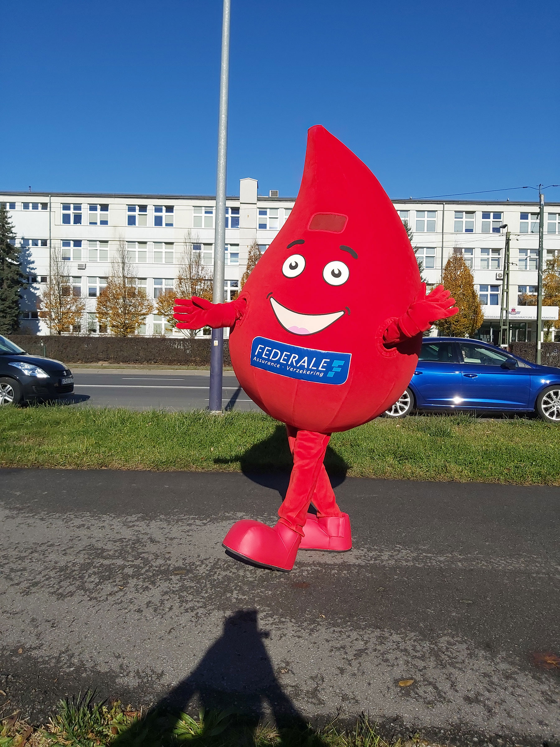 Kostium reklamowy w postaci kropli pozujący do zdjęcia obok siedziby firmy Elabika